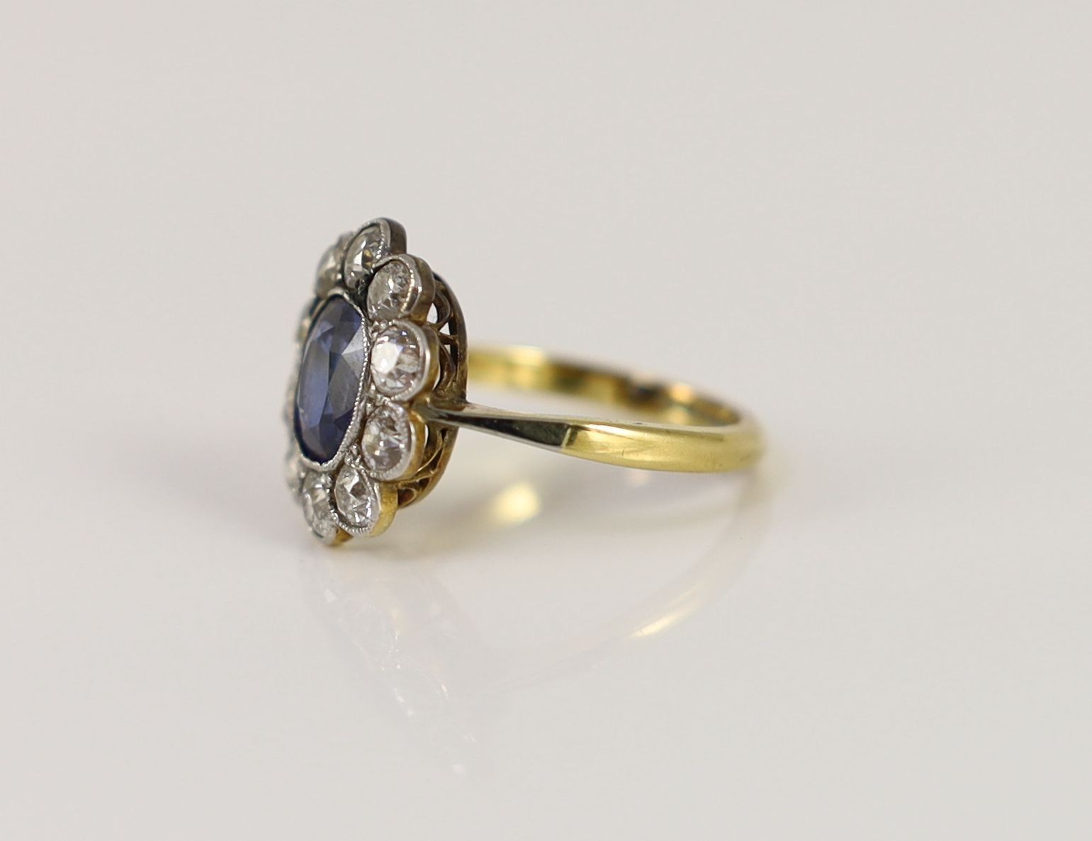 An 18ct gold and platinum, synthetic sapphire and diamond set oval cluster ring